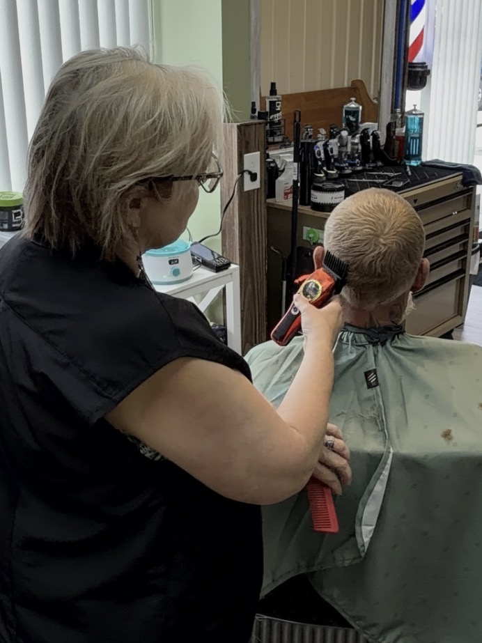Barber cutting a client's hair at Unc Style Barbershop and Suites